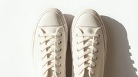 Pair of white canvas sneakers with laces on a light background, top view. Minimalist casual footwear concept for fashion and lifestyle.