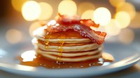 Stack of fluffy pancakes topped with crispy bacon strips and drizzled with golden maple syrup on blue plate, warm bokeh lights creating cozy breakfast atmosphere.