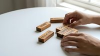 Hands arranging wooden blocks spelling HOPE WORK DREAM PLAN on white table near window for motivation and goal setting concepts.