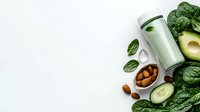 Fresh green smoothie with spinach, cucumber, avocado and almonds on white background. Healthy detox drink ingredients with copy space.