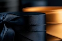 Elegant black and gold satin ribbons in soft focus create luxurious contrast, highlighting delicate texture and sheen for gift wrapping and decorative designs.