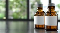 Two amber glass bottles with blank white labels and dropper caps on reflective surface against blurred window background, ready for medicine or essential oils.