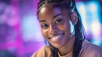 Young African American woman with braided hair smiling at camera in neon-lit environment with purple and blue bokeh lighting, suitable for lifestyle and portrait projects.