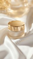 Luxury skincare cream jar with gold lid on white silk fabric, surrounded by soft bokeh lighting and golden accents, perfect for cosmetics and beauty product marketing.