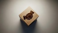 Wooden block with handshake symbol engraved on surface representing business partnership, cooperation and agreement concepts for corporate branding.