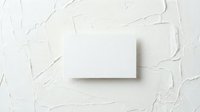 Blank white business card mockup on textured plaster wall background, top view flat lay for branding and identity design.