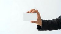 Male hand in dark business sleeve holding blank white card horizontally for corporate branding, contact information, or promotional messaging.