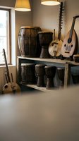 Traditional ethnic musical instruments collection featuring drums, stringed instruments and percussion displayed on wooden shelves in warm interior setting.