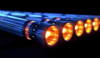 Glowing orange light beams through metallic tubes in dark background creating futuristic technological effect, modern industrial design concept.