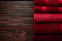 Stack of folded red terry towels on dark wooden background with copy space, showcasing soft bathroom textiles for home decor.
