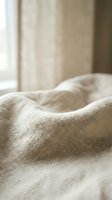 Soft beige linen fabric with natural texture and folds, ideal for home decor, bedding, and interior design projects.