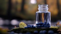 Fresh blueberries scattered around empty glass jar on moss surface with natural bokeh background for organic food storage and preservation concepts.