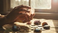Hands holding healing crystals in warm sunlight by window with collection of gemstones for meditation, spiritual wellness and energy healing practices.