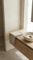 Minimalist bathroom corner with wooden vanity, white ceramic sink, folded linen towel, and natural light from window. Spa and wellness design for home decor projects.