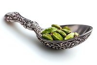 Green cardamom pods in ornate vintage silver spoon on white background, aromatic spice for cooking and flavoring food, isolated macro shot.