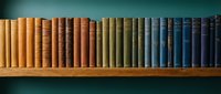 Row of vintage books with colorful spines arranged on wooden shelf against teal wall creating organized library display for education and literature concepts.