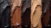 Smeared makeup foundation samples in different skin tone shades from light to dark showing texture and consistency of cosmetic products.