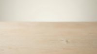 Minimalist wooden table surface with neutral beige wall backdrop, providing clean empty space for product placement, mockups, and commercial design projects.