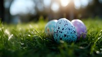 Speckled Easter eggs in vibrant blue and pink nestled in fresh spring grass with soft sunlight creating magical bokeh effect in background. Perfect for holiday designs.