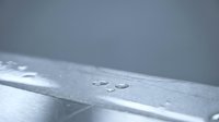 Water droplets on metallic surface with condensation creating minimalist industrial background for technology and engineering applications.