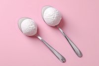 Two metal spoons with white ice cream scoops on pink background, minimalist food photography composition for menu design and social media content.