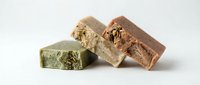 Handmade natural soap bars with dried herbs and flowers on white background. Organic skincare products for spa and wellness routines.