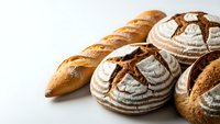 Artisan bread collection featuring crusty baguette and round sourdough loaves with decorative scoring patterns on clean white background for bakery marketing.
