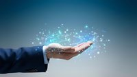 Businessman hand holding glowing digital particles and data network connections against blue background, representing technology, innovation, and business solutions.