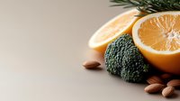 Healthy food composition with fresh grapefruit halves, raw broccoli florets, almonds and rosemary sprigs on neutral background for nutrition and wellness content.
