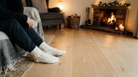 Cozy winter evening with person wearing warm socks relaxing by fireplace with glowing lights and comfortable home interior setting for seasonal comfort themes.