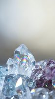 Clear quartz and amethyst crystal cluster with rainbow light reflections on neutral background for spiritual healing and meditation practices.