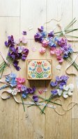 Colorful sweet pea flowers arranged around decorative wooden box on rustic wood background for crafting and floral design projects.