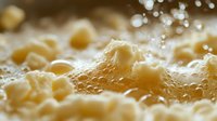 Macro shot of bubbling pasta in boiling water with steam and water droplets creating artistic bokeh effect. Fresh homemade Italian cuisine preparation.