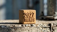 Wooden cube with engraved 2027 trends text placed on concrete surface, symbolizing future business forecasting and planning concepts.