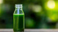 Fresh green smoothie juice in glass bottle on wooden table with blurred natural background for healthy lifestyle and detox diet concepts.