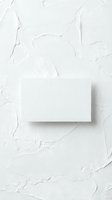 Blank white business card mockup on textured plaster wall background for branding and corporate identity design projects.