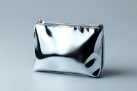 Metallic silver cosmetic bag with zipper closure on gray background, minimalist luxury accessory for makeup and beauty products storage, modern fashion design.