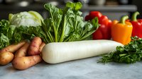 Fresh organic vegetables including daikon radish, potatoes, bell peppers, lettuce and herbs arranged on gray stone counter, selective focus on white radish.