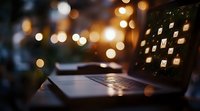 Laptop keyboard silhouette against blurred warm bokeh lights background, creating cozy evening atmosphere for remote work and productivity setup.