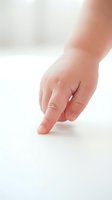Newborn infant hand with finger extended on white surface, isolated against neutral background for healthcare and parenting content.