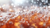 Macro photography of transparent water bubbles against blurred orange and white bokeh background creating dreamy abstract composition with light reflections.