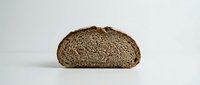 Sliced whole wheat bread loaf half showing dense crumb structure and texture, suitable for food photography, bakery marketing, and culinary publications.
