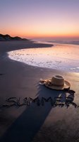 Summer written in sand on a sunset beach with straw hat and sunglasses, warm golden sky reflecting on wet shoreline.