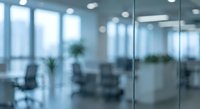 Blurred modern office interior with glass partitions and conference room. Corporate workspace background for business presentations and professional content.