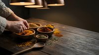Hands arranging colorful spices in wooden bowls on rustic table with warm lighting for culinary cooking and food preparation in kitchen setting.