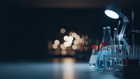 Laboratory glassware and equipment on research table with bokeh lights creating professional scientific workspace atmosphere for medical studies.