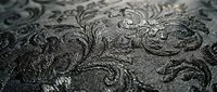 Ornate embossed metallic surface with intricate swirling patterns and decorative flourishes, suitable for luxury branding, backgrounds, and design projects.