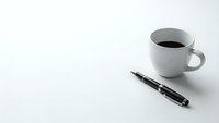 Minimalist workspace with white coffee cup and black pen on clean white surface for business and office productivity concepts.