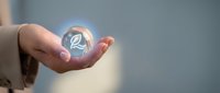 Businesswoman holding glowing eco leaf symbol in cupped hands representing sustainable business practices and environmental responsibility in corporate setting.