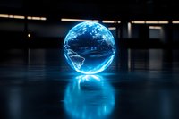 Glowing blue holographic Earth globe floating in dark space with reflection on glossy surface, futuristic technology visualization concept.